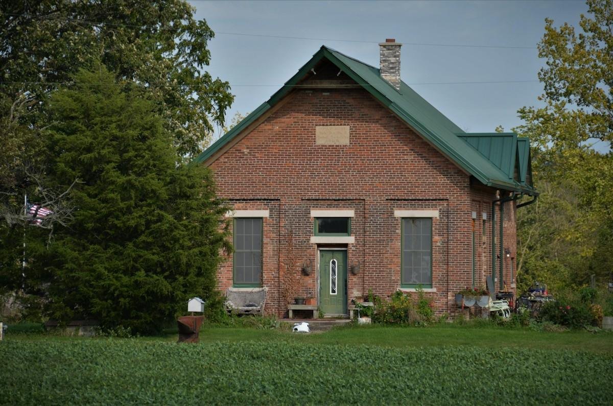 An old brick farmhouse with a green standing-seam metal roof