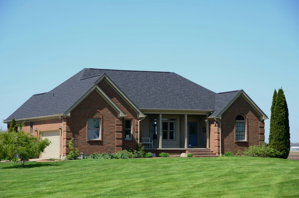 A brick ranch house with a dark architectural shingle roof
