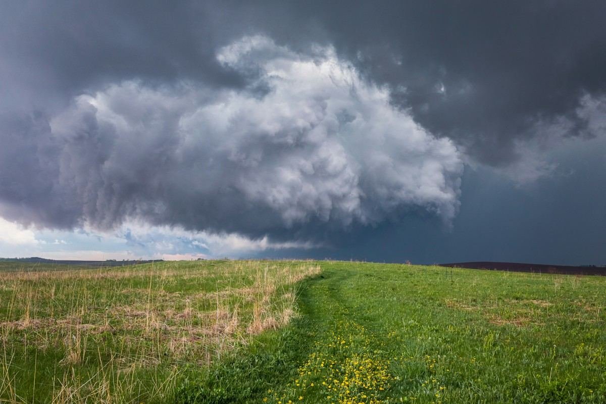 A low storm cloud moving over a green field