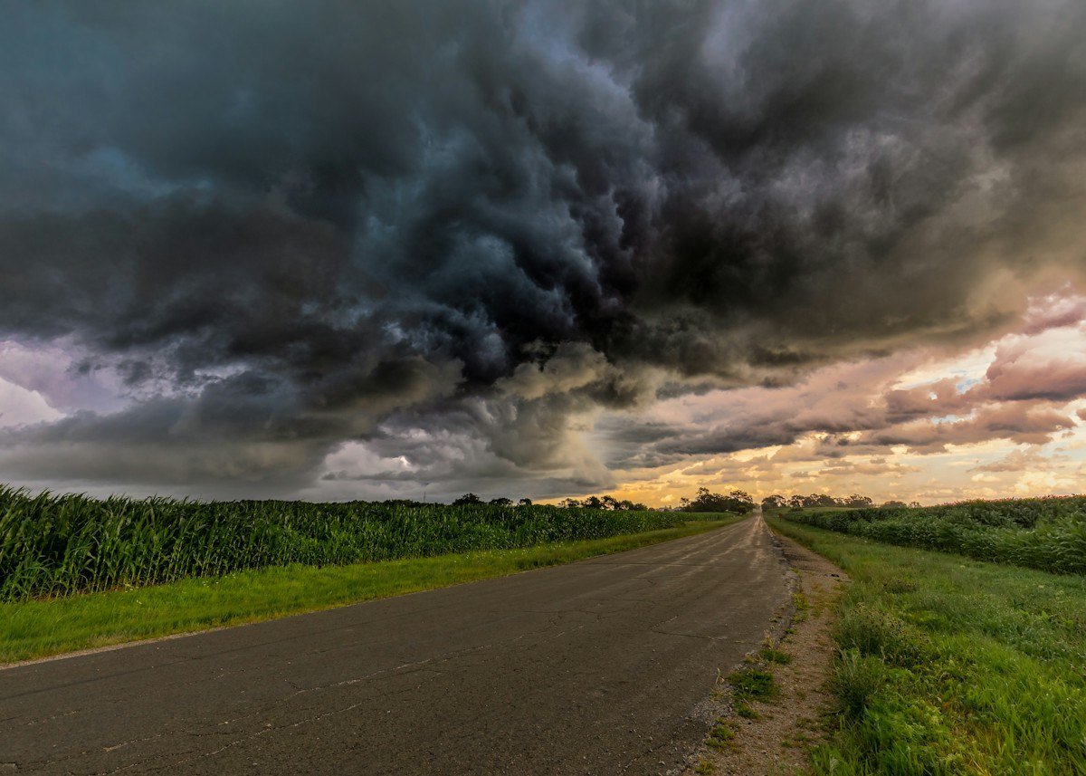 Dark storm clouds over a country road between cornfields