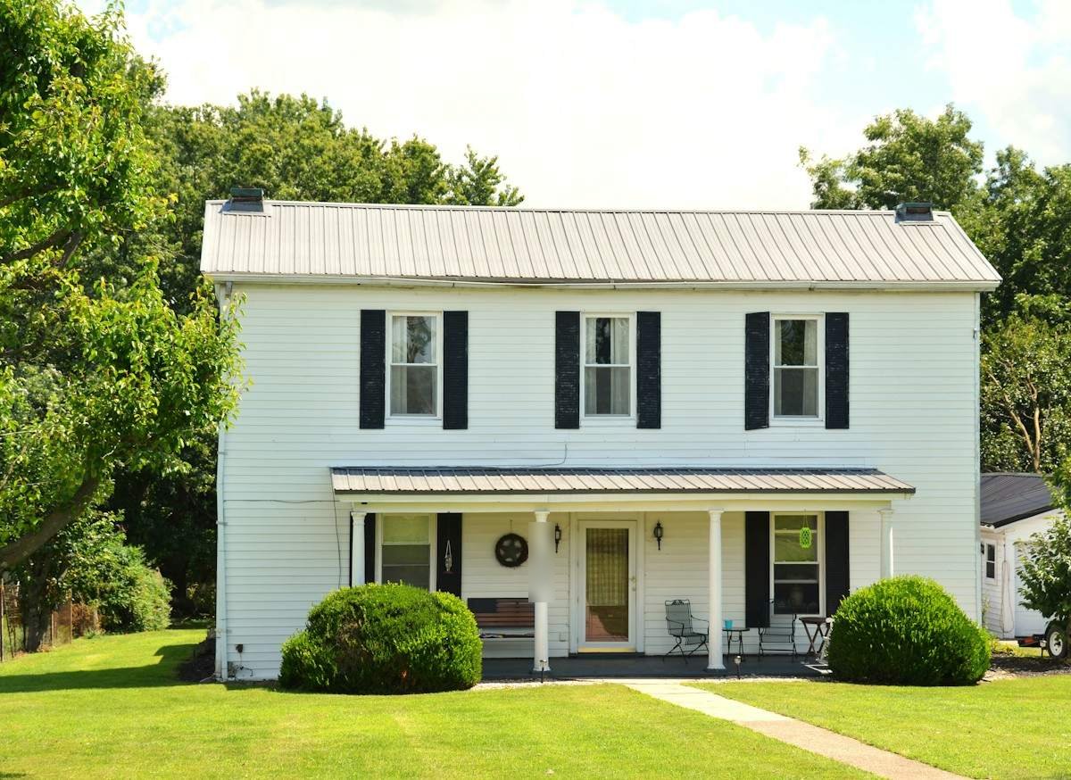 A white two-story farmhouse with a gray metal roof